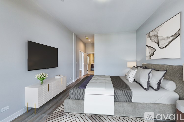 A modern bedroom with a large bed and a flat screen TV mounted on the wall.