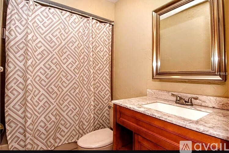 A bathroom with a marble counter top and a patterned shower curtain.