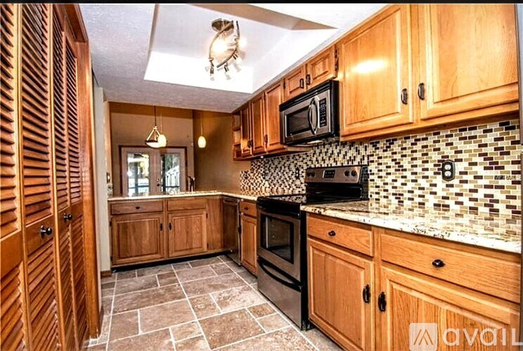 A kitchen with wooden cabinets and a black and white tiled backsplash.
