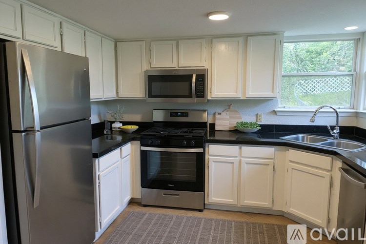 A kitchen with white cabinets and a black countertop.