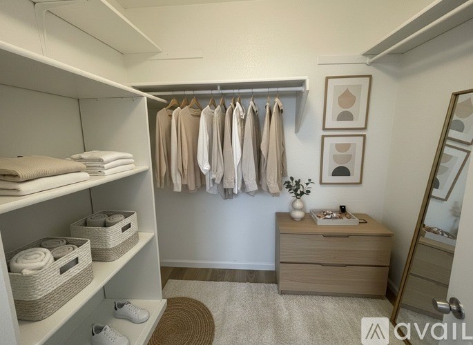 A well-organized bedroom with clothes hanging on a rail and towels neatly stacked on shelves.