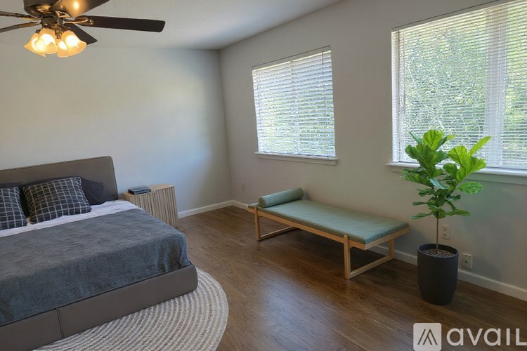A bedroom with a bed, bench, and potted plant.