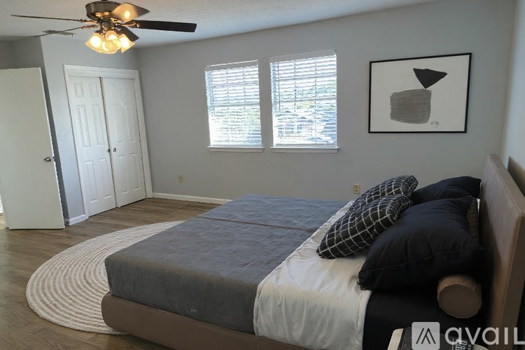 A bedroom with a bed, pillows, a ceiling fan, and a window with blinds.
