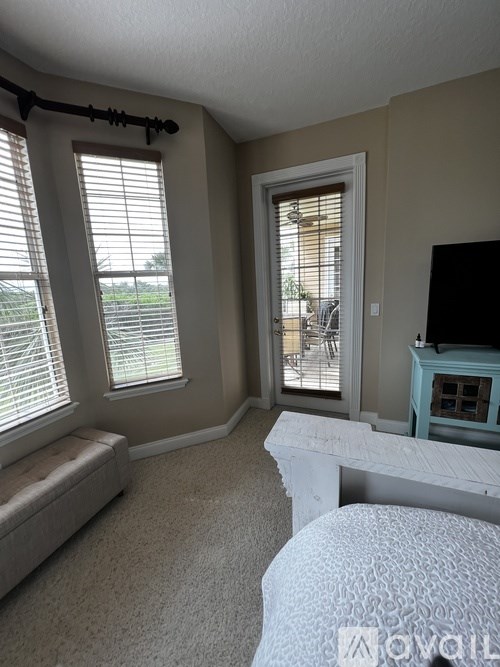 A bedroom with a bed, window, and sliding glass door.
