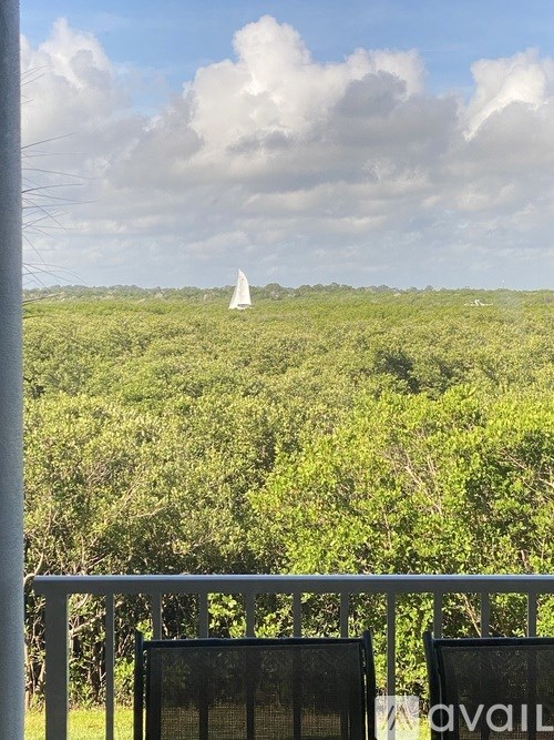 A white sailboat is in the distance on a green landscape.