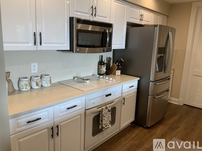 A kitchen with white cabinets and a stainless steel refrigerator.