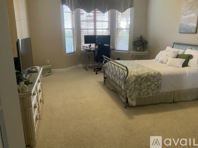 A bedroom with a bed, desk, and television.