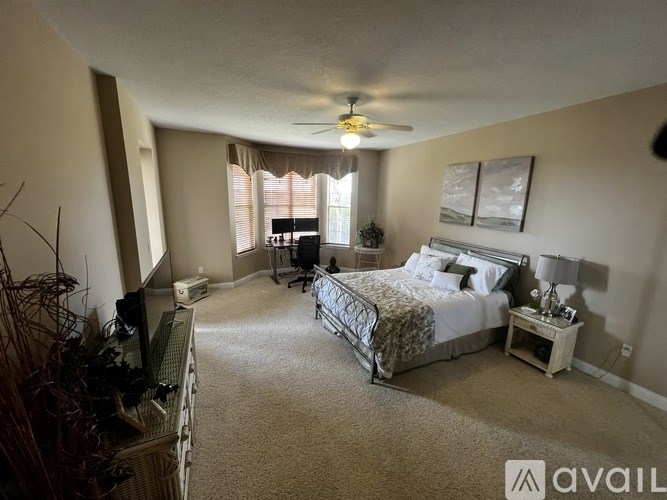 A bedroom with a bed, a television, and a window with curtains.
