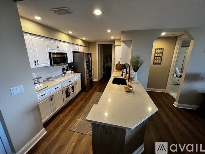 A kitchen with a white island and wooden floors.