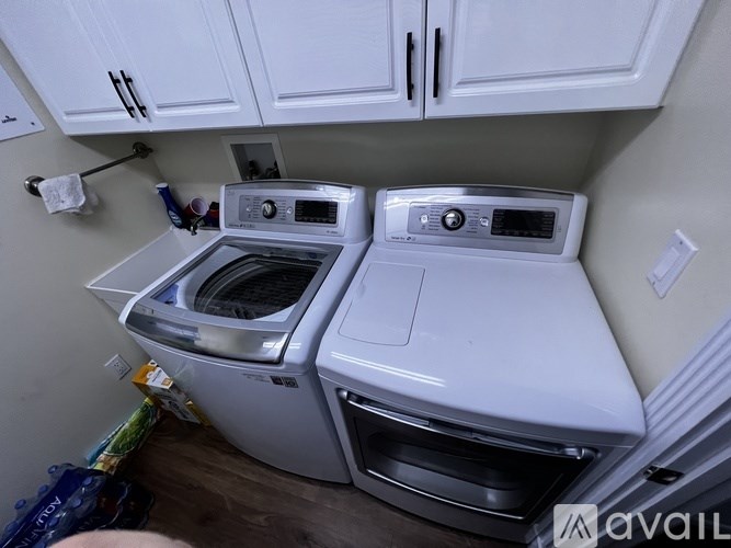A white dishwasher and dryer are stacked in a small kitchen.