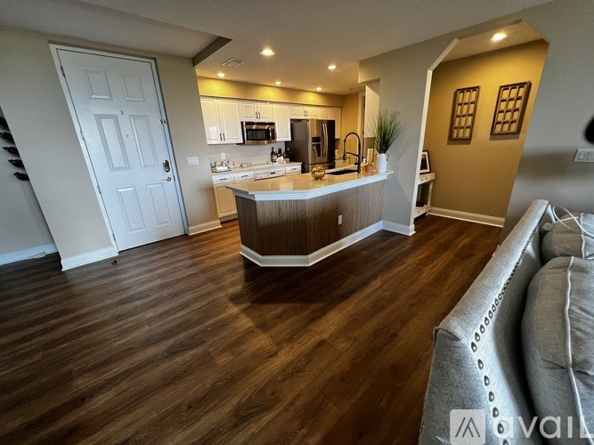 A kitchen with a white door and a wooden floor.