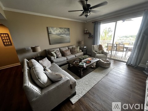 A living room with a grey couch and a painting on the wall.