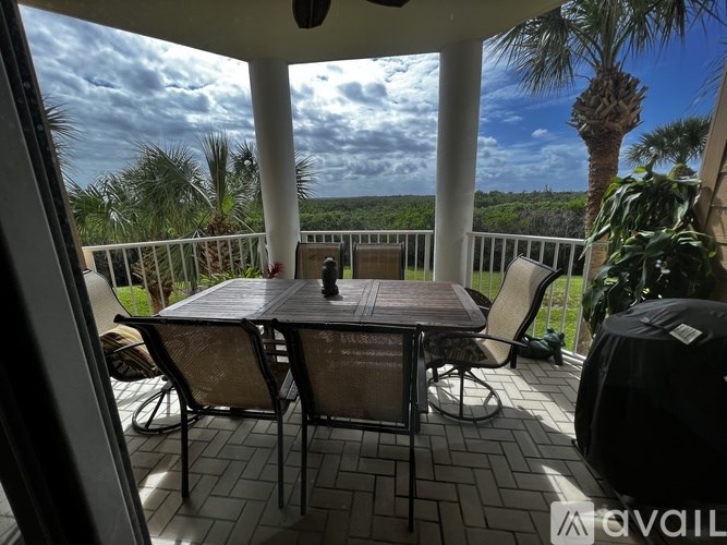 A patio with a table and chairs overlooking a forest.
