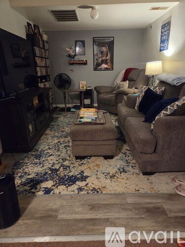 A living room with a brown couch, a coffee table, and a rug with blue flowers on it.