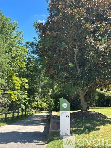 A signpost in a park with trees in the background.