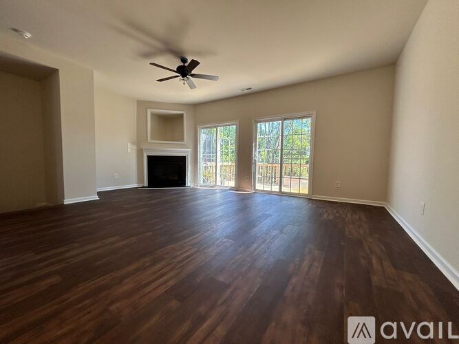 A spacious room with wood flooring and a ceiling fan.