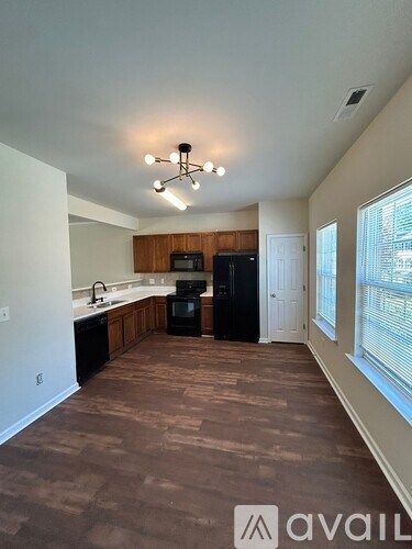 A kitchen area with a black refrigerator and a microwave.