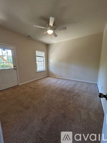 A room with a carpeted floor and a ceiling fan.