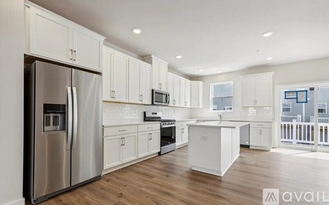 A modern kitchen with white cabinets and stainless steel appliances.