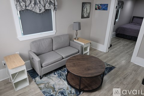A living room with a grey couch, a wooden coffee table, and a lamp on a side table.