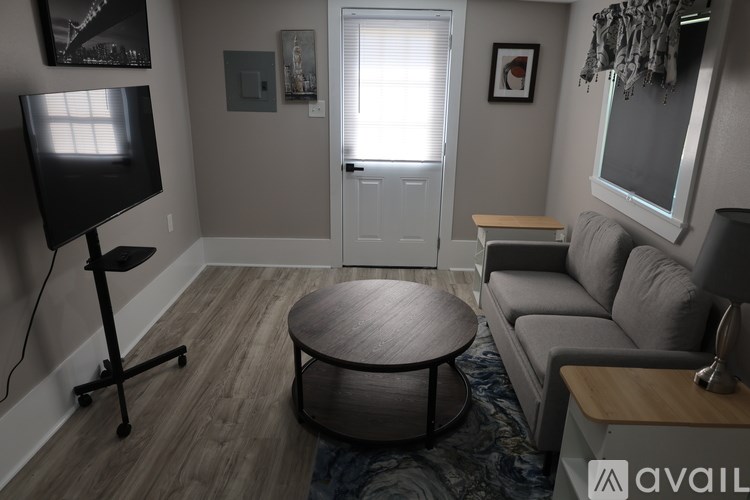 A living room with a grey couch, a black TV, and a wooden coffee table.