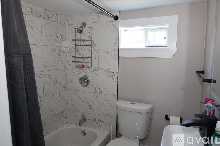 A bathroom with a marble tiled shower and a white toilet.