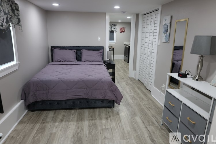 A bedroom with a purple bedspread and a black headboard.