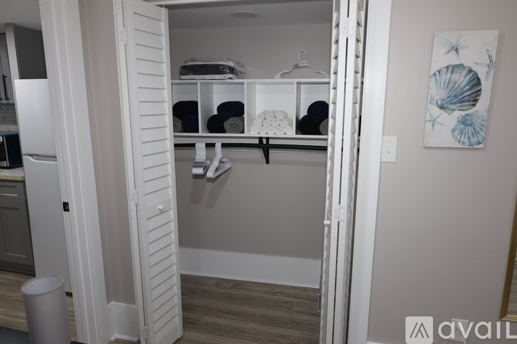 A white closet with a shelf and a painting of a seashell on the wall.