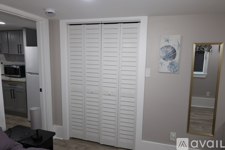 A white sliding door in a room with a mirror and a painting.