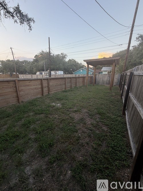 A backyard with a wooden fence and a grassy area.