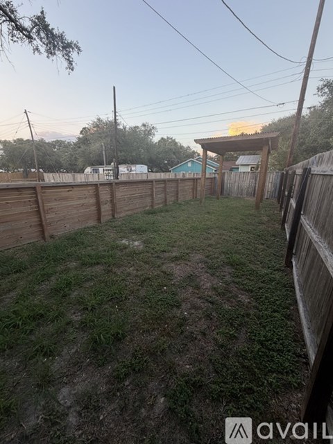 A backyard with a wooden fence and a grassy area.