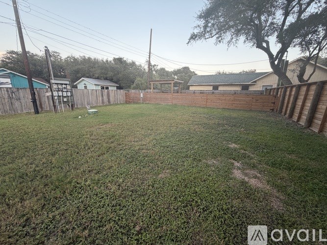 A backyard with a fence and a tree.