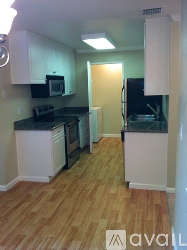 A kitchen with wooden floors and black countertops.