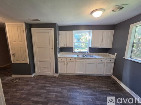 A kitchen with white cabinets and a window.