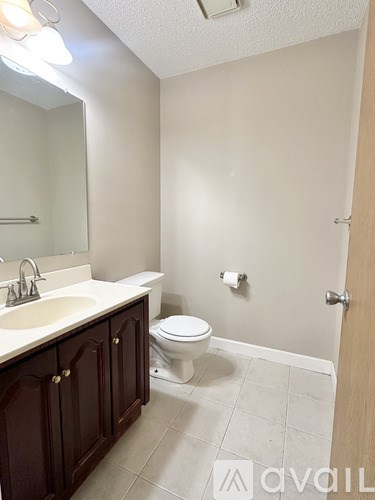 A bathroom with a toilet, sink, and mirror.