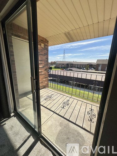 A view from a window looking out to a courtyard with a fence and a building in the distance.