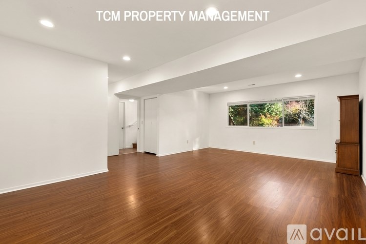 A spacious room with wooden flooring and white walls, managed by TCM Property Management.