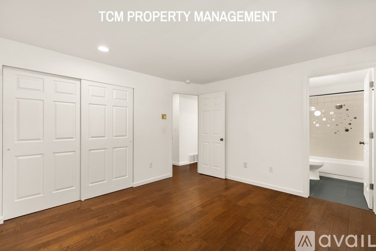 A room with white doors and wooden floors is managed by TCM Property Management.