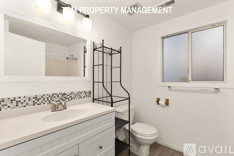 A bathroom with a toilet, sink, and mirror.