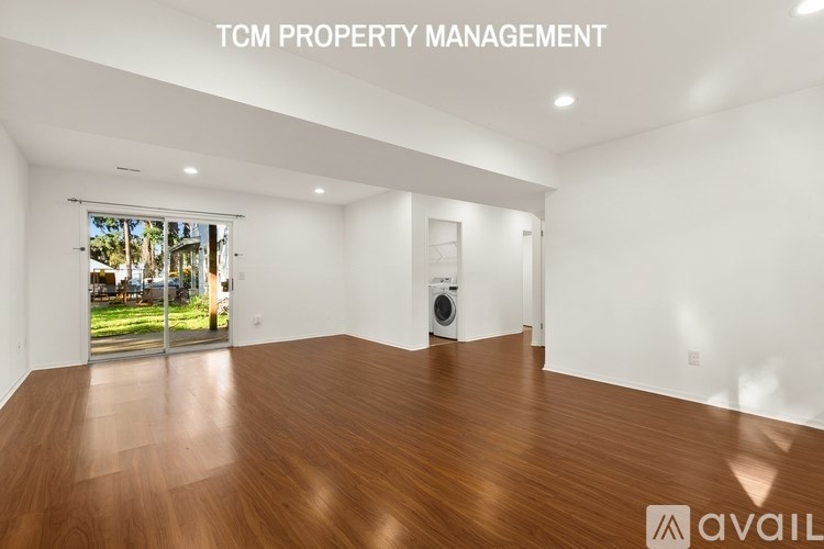 A room with wooden flooring and a window overlooking a garden.