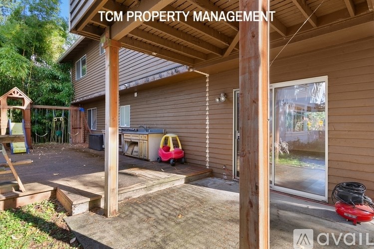 A house with a brown siding and a porch with a red lawnmower on it.