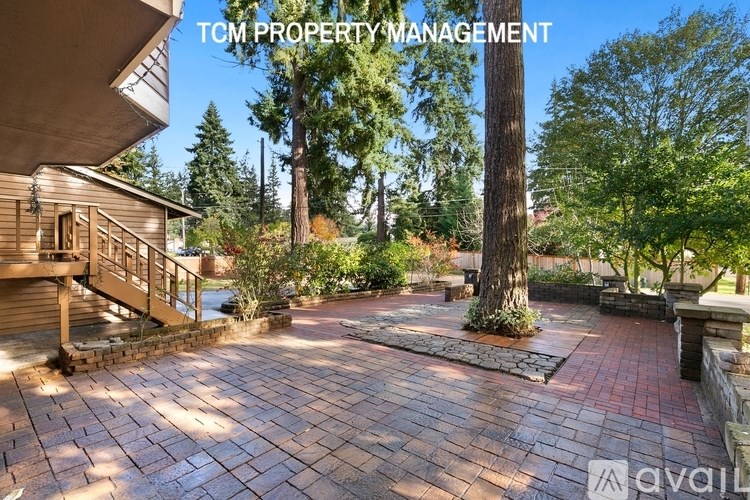 A backyard with a brick patio and a tree in the middle.