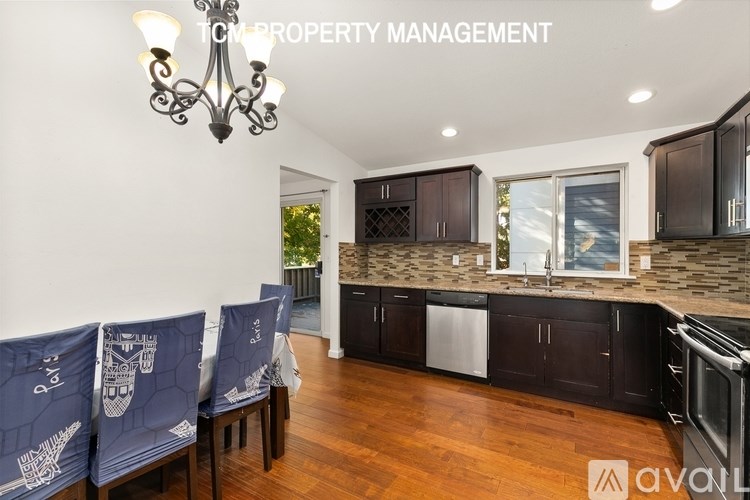 A modern kitchen with dark wood cabinets and a stone backsplash is on the market.