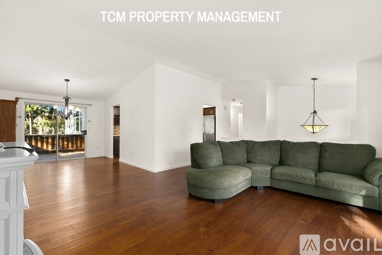 A living room with a green couch and wooden floors.