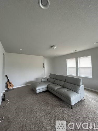 A living room with a grey couch and a guitar on the wall.