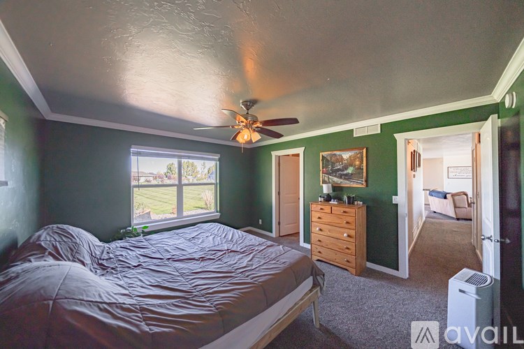 A bedroom with a bed, dresser, and window.