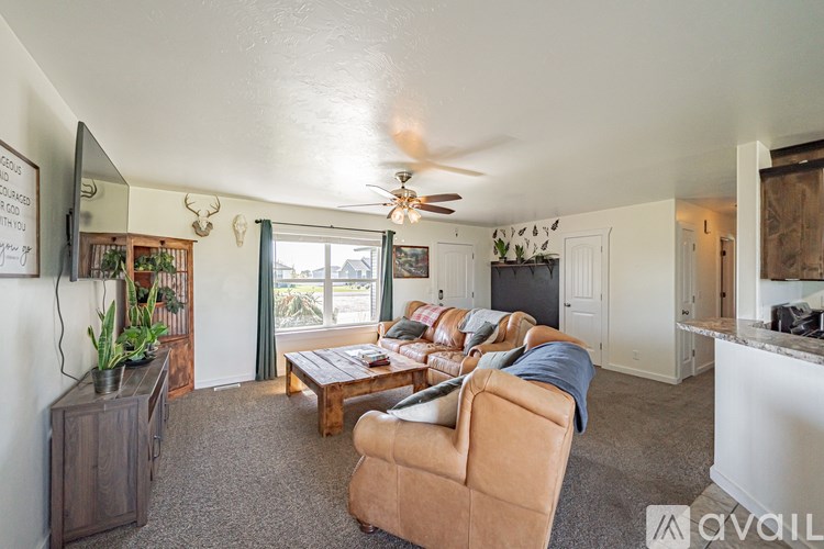 A living room with a couch, a chair, a coffee table, a ceiling fan, and a flat screen TV.