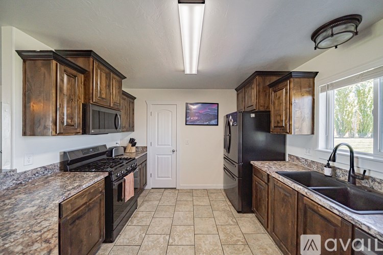 A kitchen with wooden cabinets and a black refrigerator.