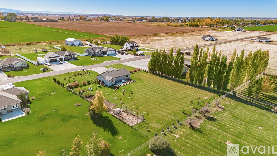 A large grassy area with a few houses and trees.