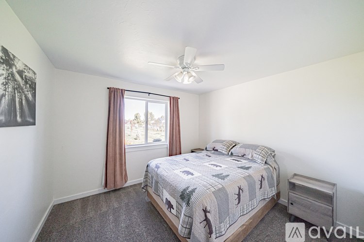 A bedroom with a bed, dresser, and window with curtains.